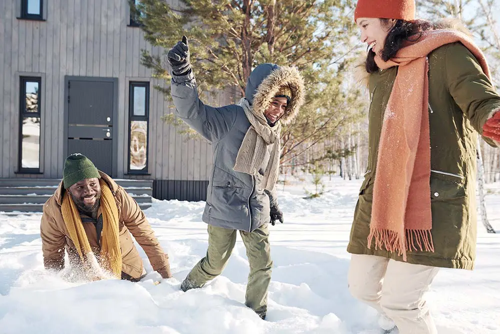 Family playing in the snow outside a Colorado home, highlighting the importance of winter pest control Colorado to keep homes safe and comfortable.